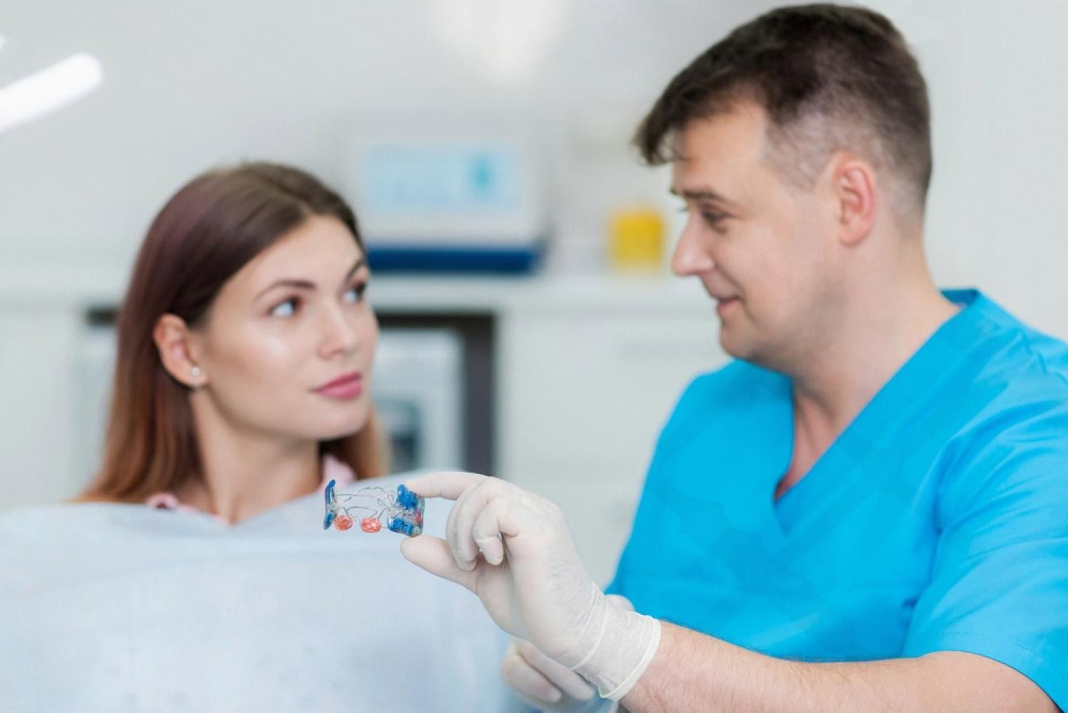 Orthodontist in Abu Dhabi showing an orthodontic appliance to a young female patient